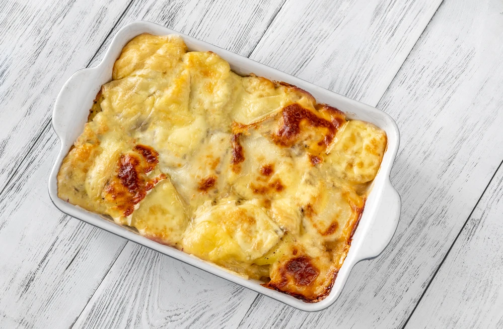Plat de tartiflette vu du dessus, gratin doré mêlant pommes de terre, reblochon fondu, lardons et oignons, symbole gourmand de la cuisine savoyarde.